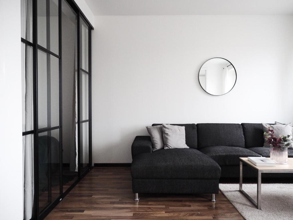 a living room with a black couch and a mirror at 2ndhomes Tampere "Hatanpää" Apartment - Newly Renovated Downtown Apt in a Historic Building in Tampere