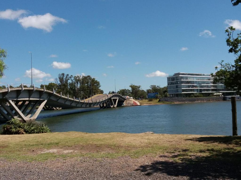 a bridge over a river with a building in the background at ITALIA RANCH in Punta del Este