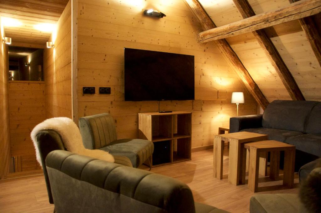 - un salon avec une télévision, un canapé et des chaises dans l&#39;établissement Chalet Le Petit Plus, à Vaujany