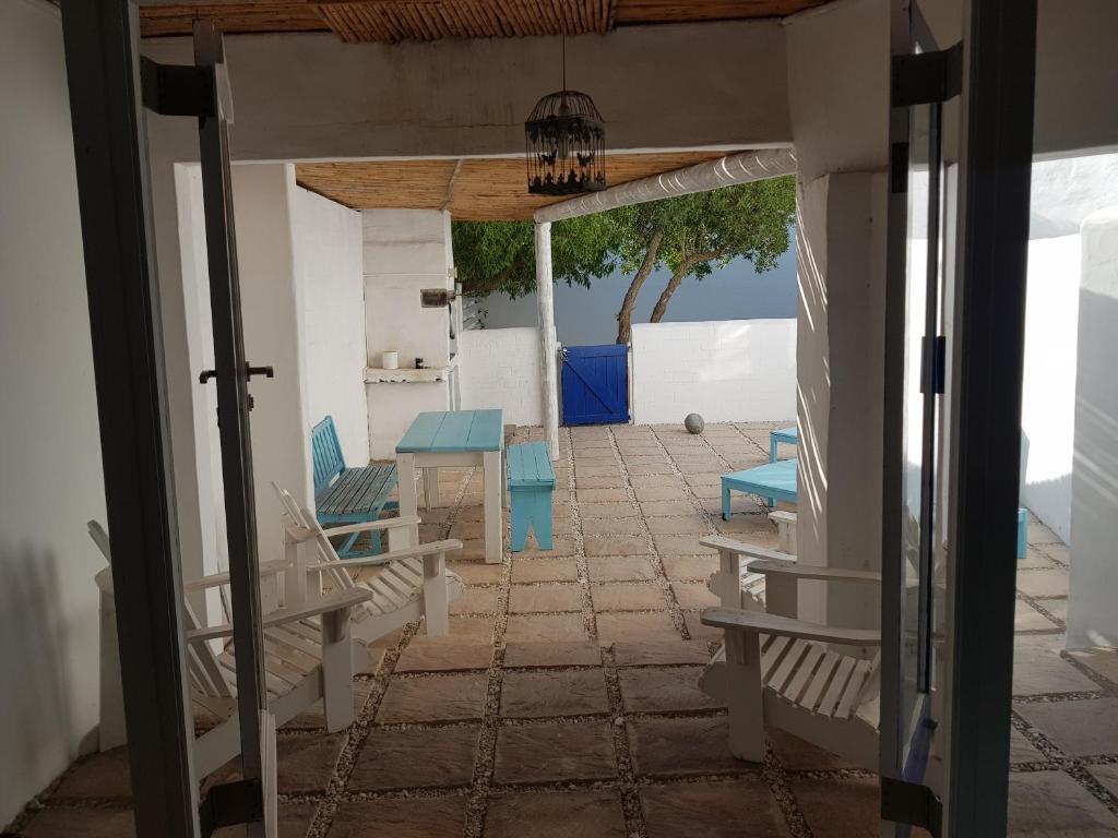 - une terrasse couverte avec des chaises bleues et une table dans l'établissement Mosselbank Beach Retreat 2, à Paternoster
