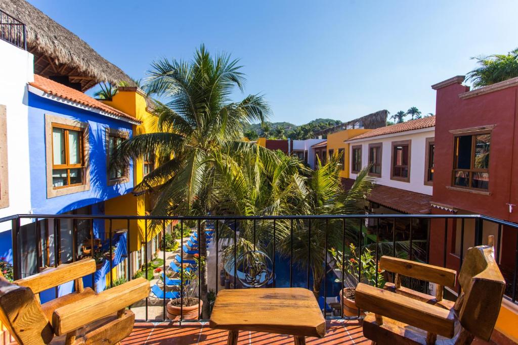 a balcony with wooden benches and a palm tree at Casa Lotería Sayulita - Family Boutique Hotel with Spacious Full Kitchen Suites, Restaurant, Rooftop Yoga, Pool & Free Parking - 3 min to Beach in Sayulita