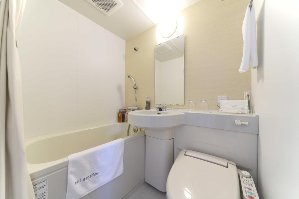 a white bathroom with a sink and a toilet at Meitetsu Inn Hamamatsucho in Tokyo