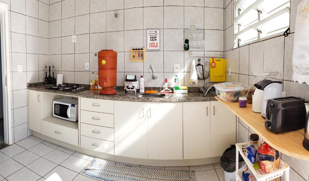 a kitchen with white cabinets and a counter top at Pequi hostel in Florianópolis