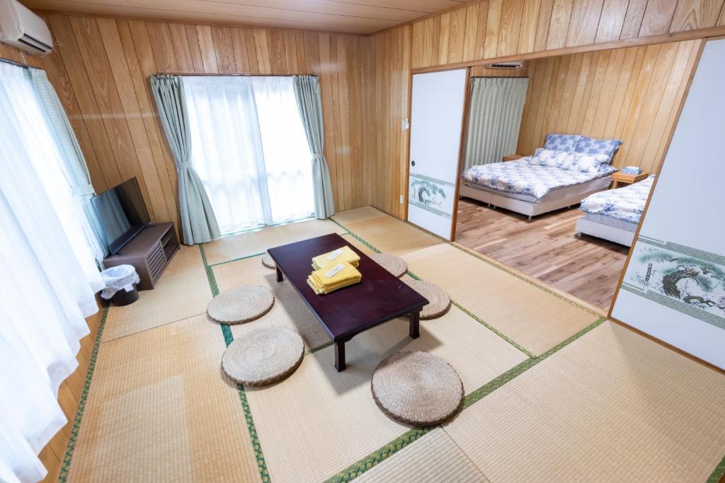 a living room with a table and two stools at kamekamehouse in Tokashiki