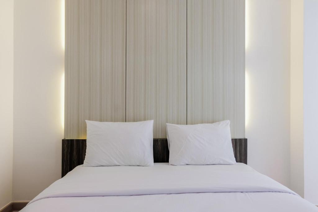 タンゲランにあるFully Parquette City View Studio Apartment at M-Town Residence By Travelioのベッド1台(白いシーツ、枕2つ付)