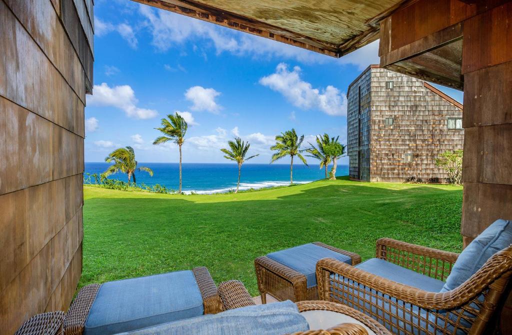 a patio with chairs and a view of the ocean at Oceanfront Condo with panoramic views! in Princeville