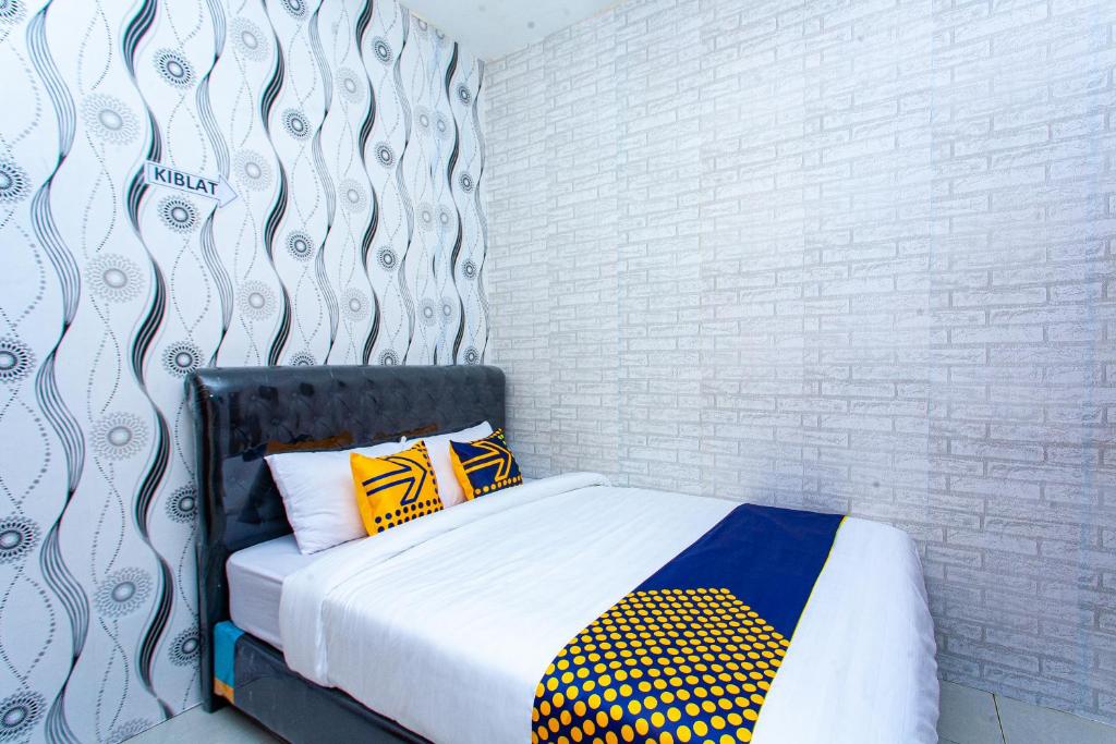 a bed with two pillows and a wall at SPOT ON 2875 Kost Pandawa Syariah in Cilacap