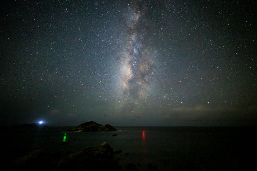 a milky way over a beach at night at kamekamehouse in Tokashiki