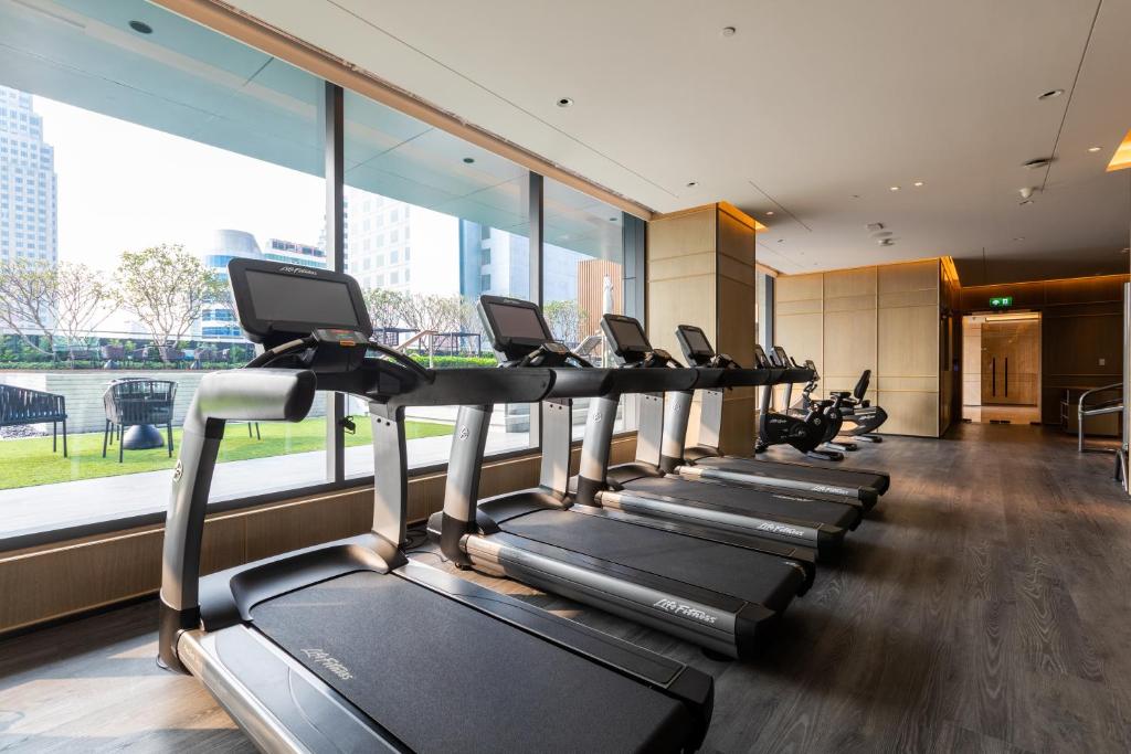 A row of treadmills beside the gym’s large windows.