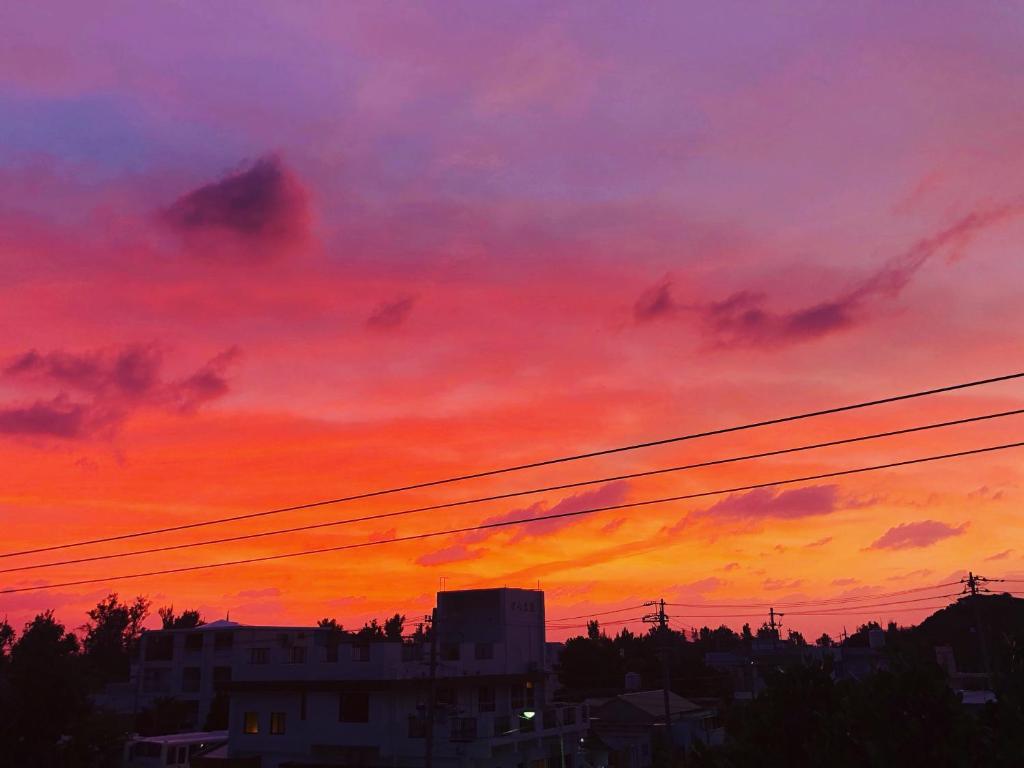 a colorful sunset with power lines in the foreground at kamekamehouse in Tokashiki