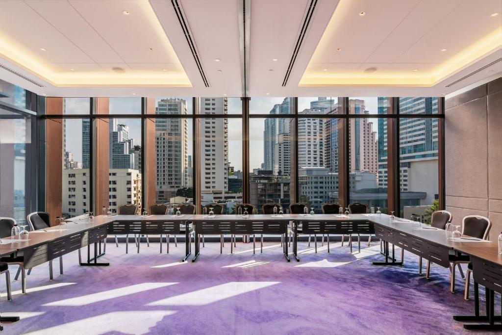 A flexible conference room with U-shaped tables, city-facing windows, and bright natural light.