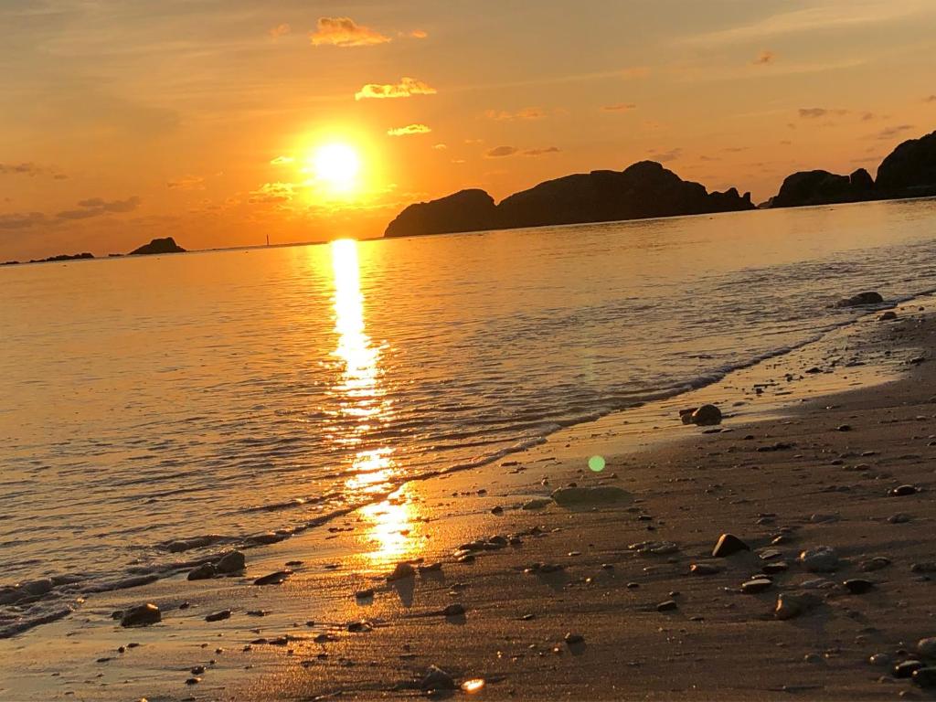 a sunset on a beach with the sun setting at kamekamehouse in Tokashiki