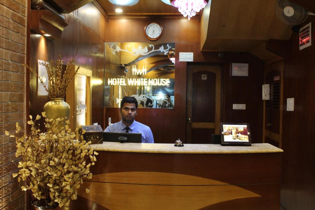 Ein Mann, der mit einem Laptop an einer Bar sitzt. in der Unterkunft Hotel White House in Kalkutta