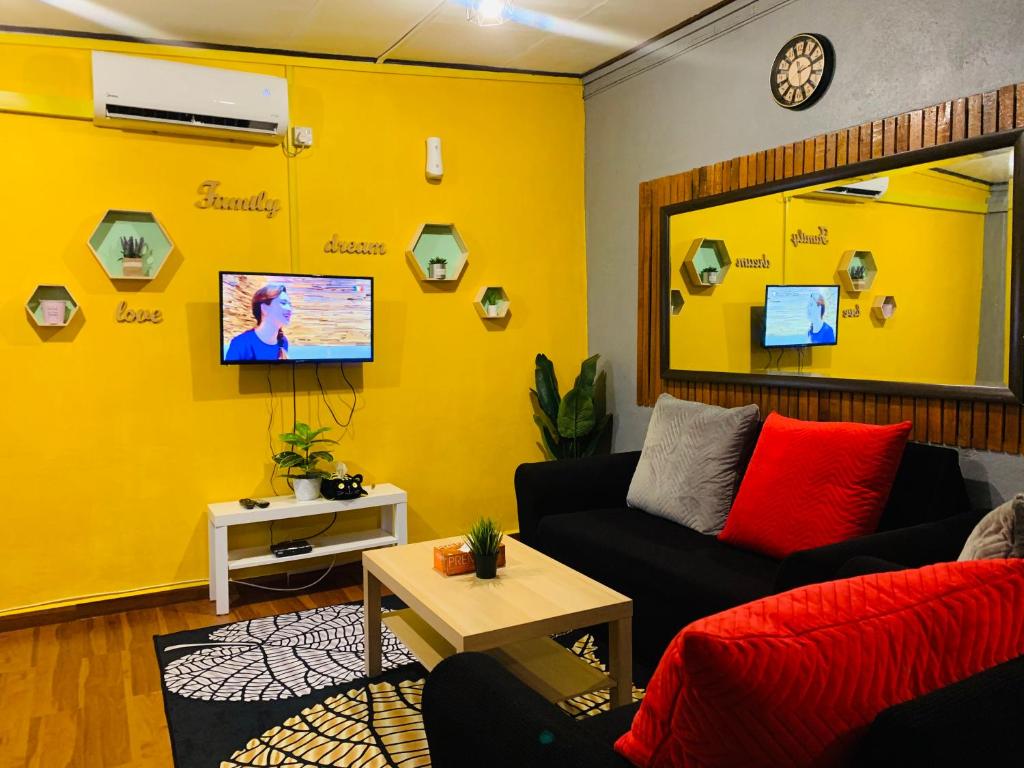 a living room with a couch and a yellow wall at Ammar Homestay in Kuala Terengganu