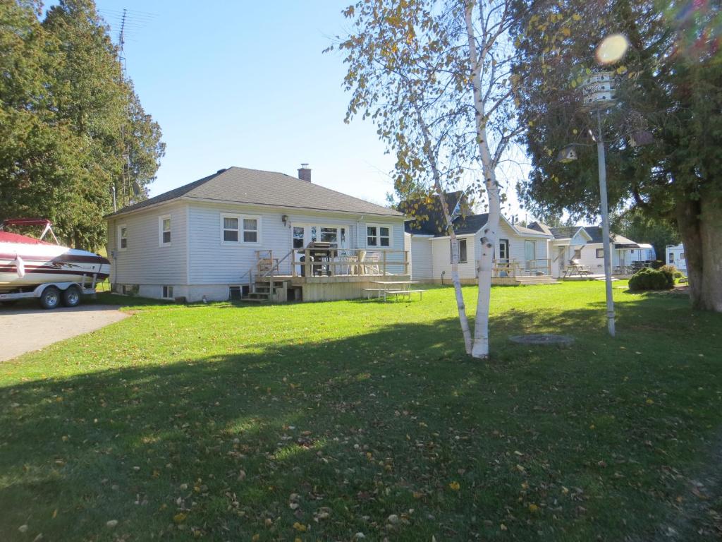 a house with a tree in the yard at Lunge Haven Cottages & Boating Club in Lindsay