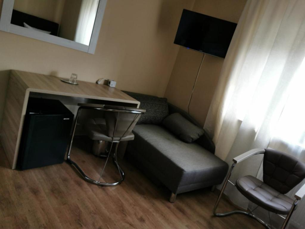a room with a couch and a table and a desk at Hotel-Residenz Oberurseler Hof in Oberursel