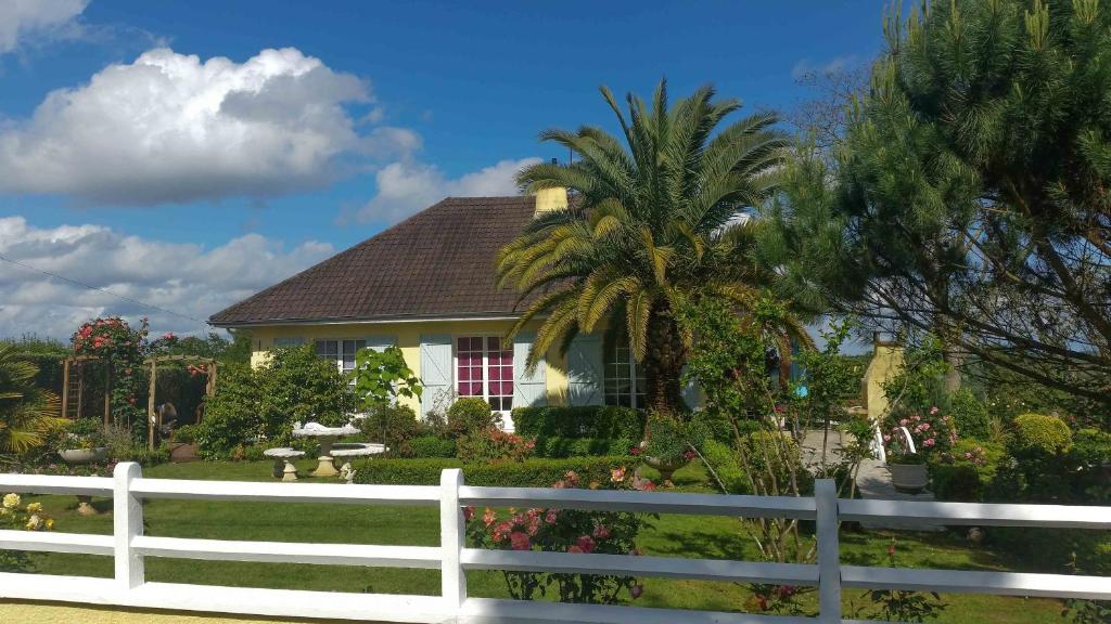 a white fence in front of a house with a palm tree at O'jardin in Arthez-de-Béarn