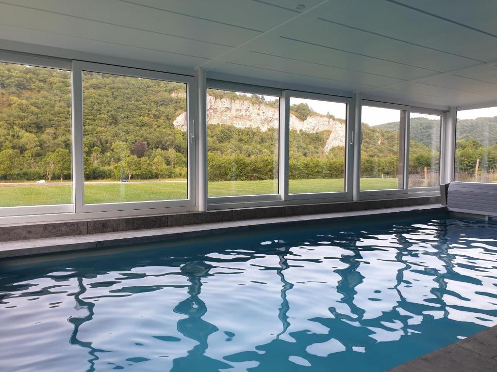 een zwembad in een huis met ramen bij Le Val des Cerfs - Het Hertendal in Hastière-par-delà