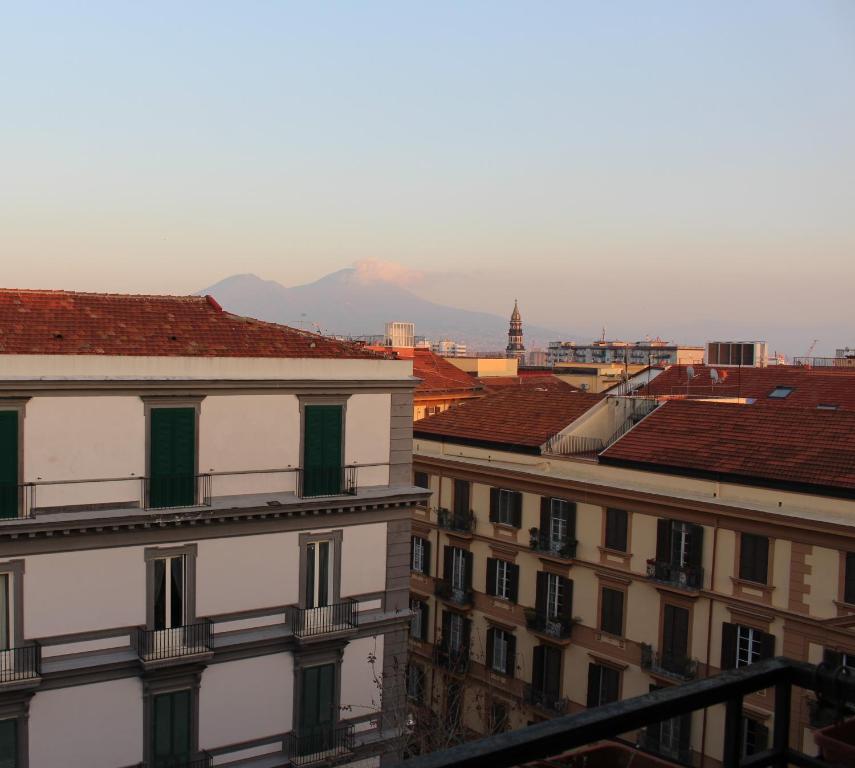 une vue sur les toits des bâtiments avec des montagnes en arrière-plan dans l'établissement Maison Duomo 290, à Naples