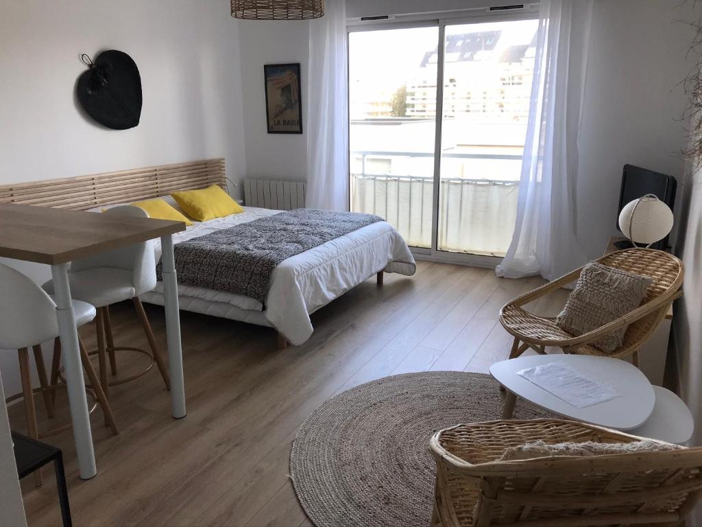une chambre avec un lit, une table et une fenêtre dans l'établissement Studio neuf , à 2 pas de la plage et du port, au Pouliguen