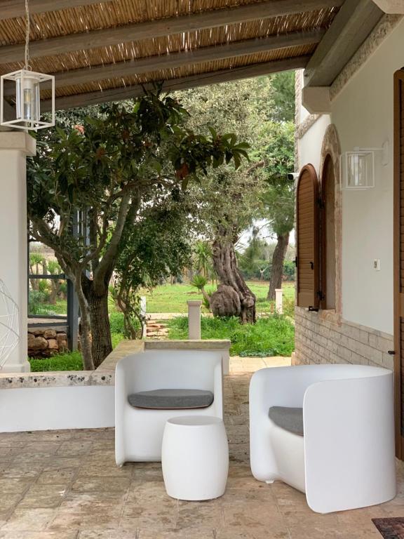 a patio with two white chairs and a table at Trullo Labellavita in Putignano