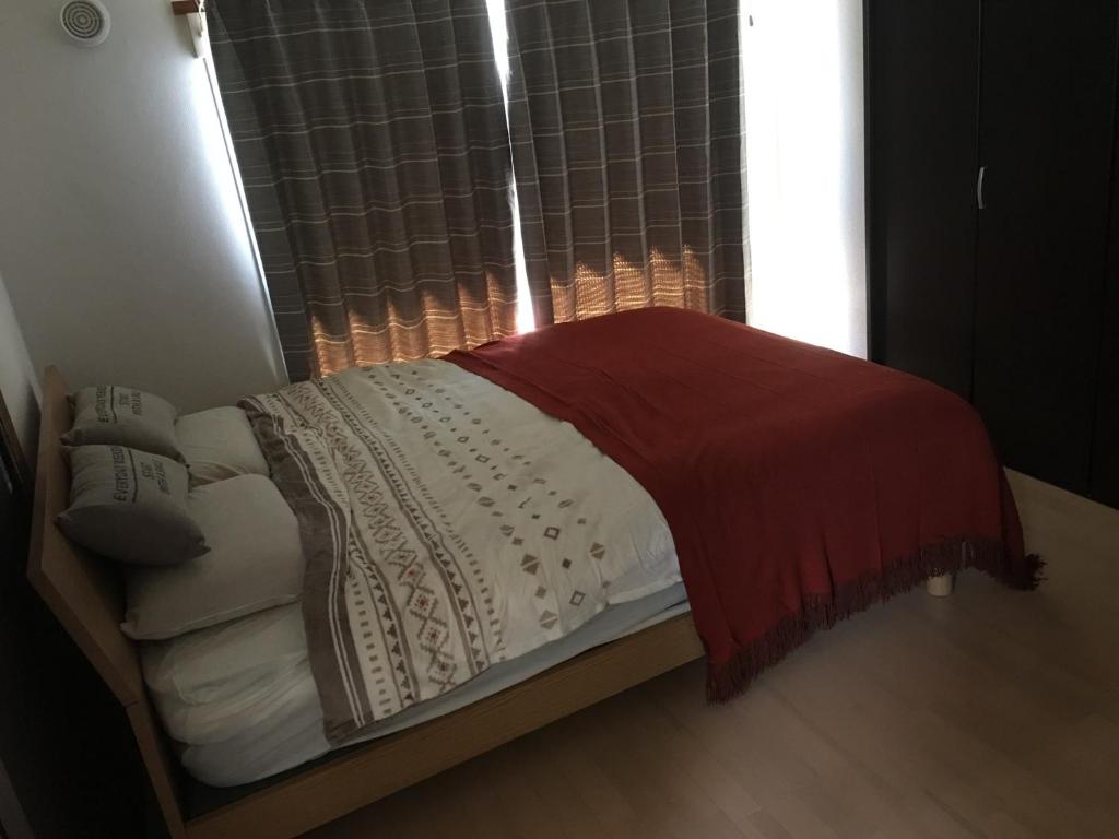 a bed with a red blanket and a window at G&R House 201 in Tokyo