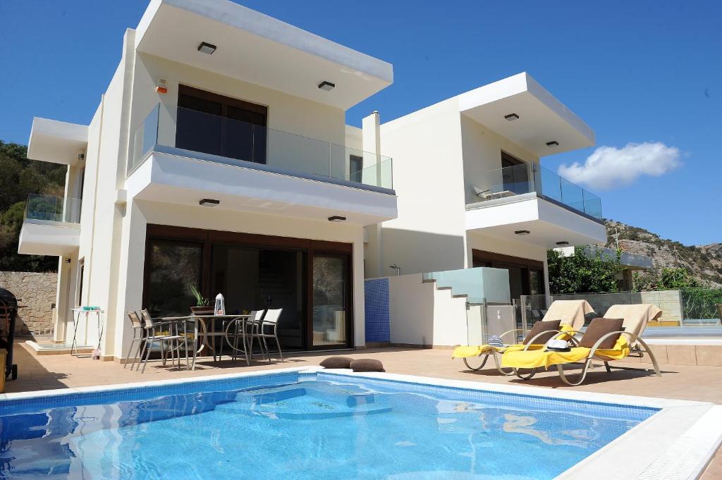 a villa with a swimming pool in front of a house at Palaiokastro Villas & Suites in Palaiokastro