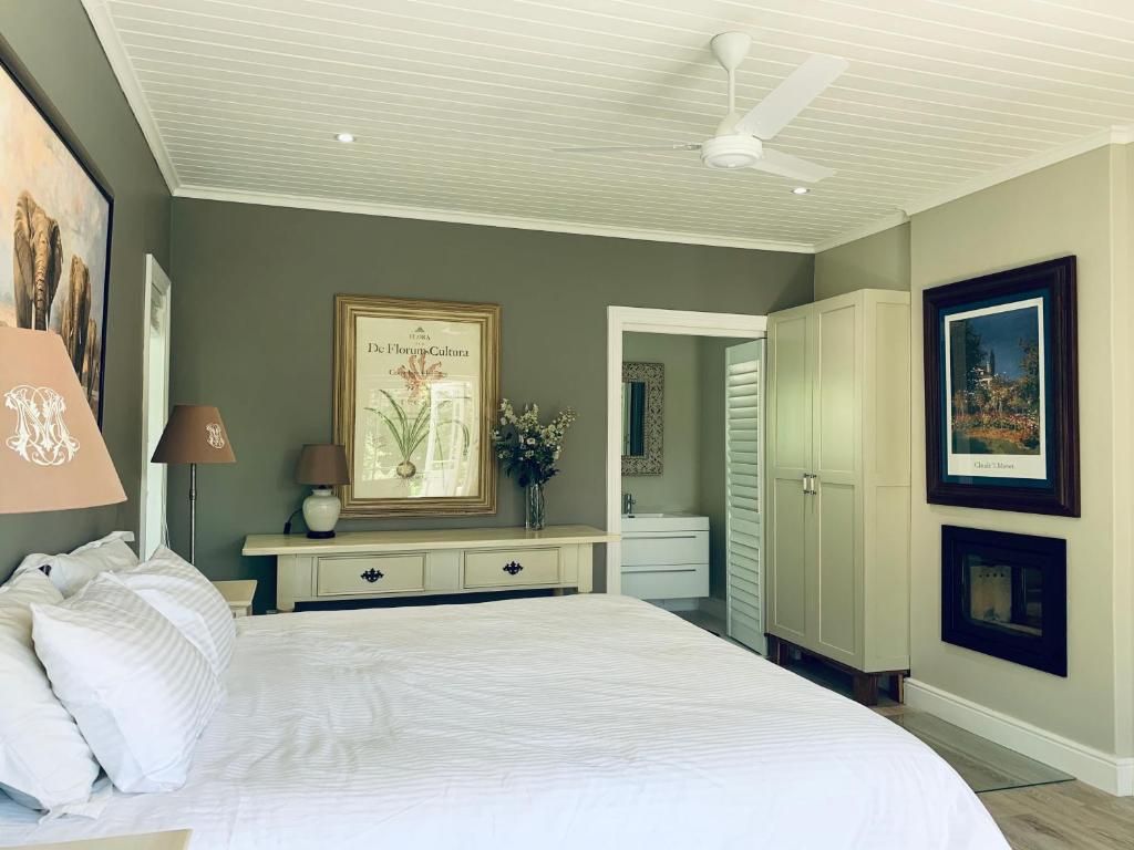 um quarto com uma cama branca e uma ventoinha de tecto em One Oak Guest House em Somerset West
