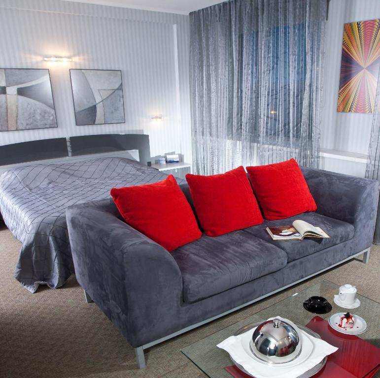 ein Schlafzimmer mit einem Sofa und einem Bett mit roten Kissen in der Unterkunft Don Plaza Congress Hotel in Rostow am Don