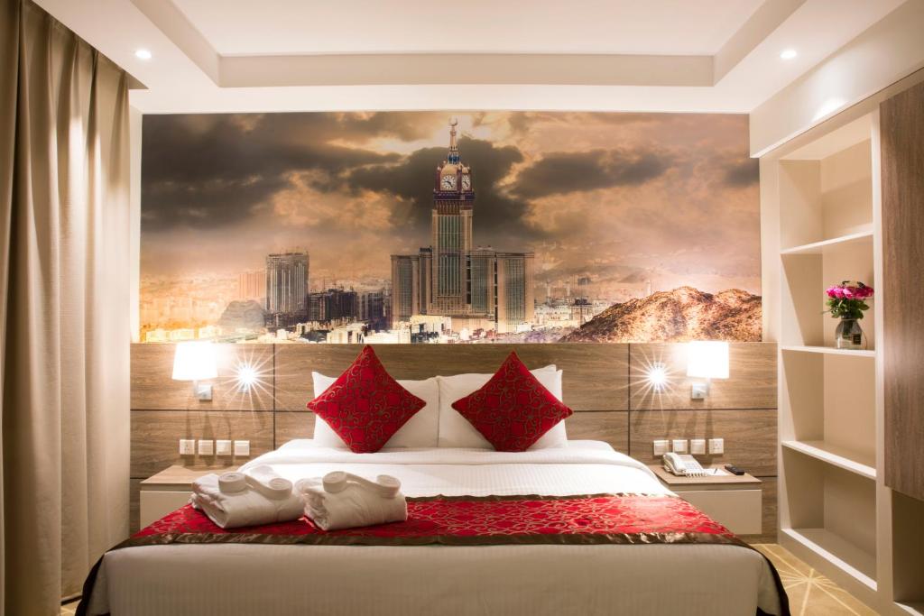 a bedroom with a large bed with a city painting on the wall at Hibatullah Hotel Makkah in Mecca