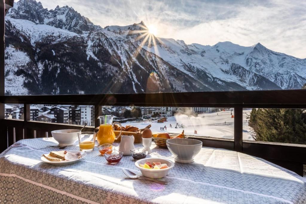 a table with food and a view of a mountain at Les Balcons du Savoy in Chamonix-Mont-Blanc