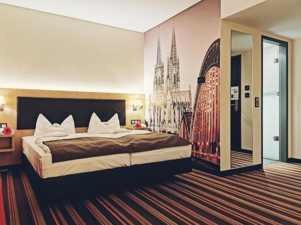 ケルンにあるホテル フォーチュンの大きなベッドと大聖堂の写真が備わるベッドルーム1室が備わります。