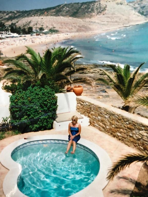 a woman sitting in a swimming pool next to a beach at Beach front/waterside apartment in Luz