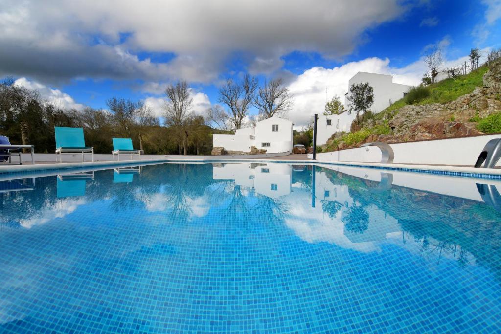 una gran piscina de agua azul frente a un edificio en Moinho da Capela en Campo Maior