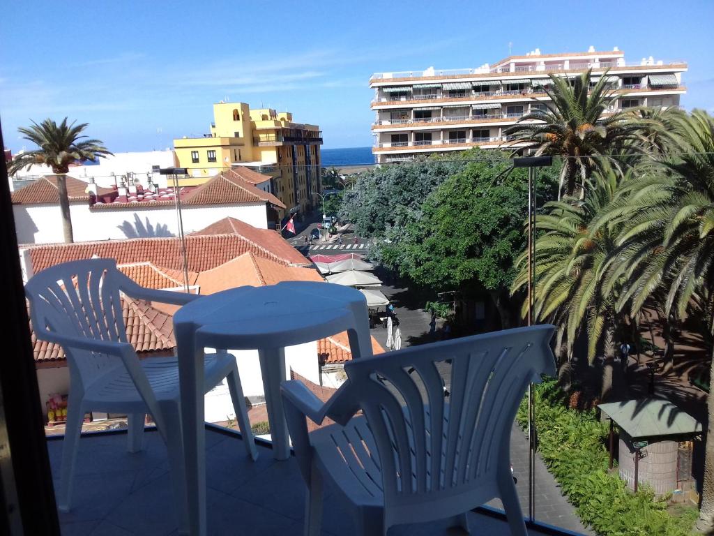 un balcón con 2 sillas y una mesa y un edificio en Hotel Tropical en Puerto de la Cruz