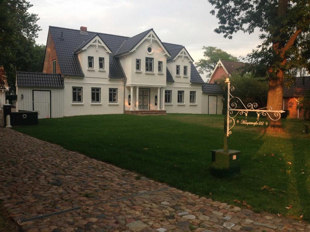 a white house with a sign in the yard at Ferienwohnungen Bekperle in Bekdorf