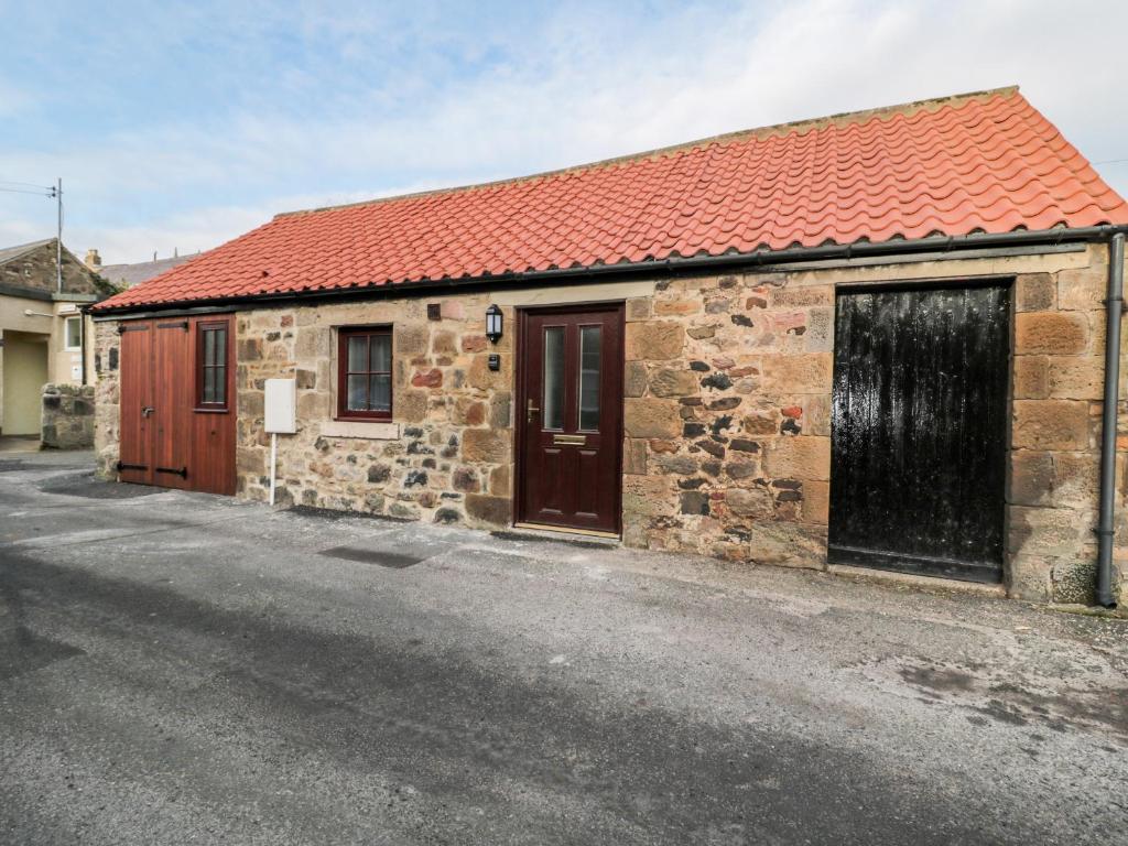 an old stone building with a red roof and a street at The Old Stables in Belford