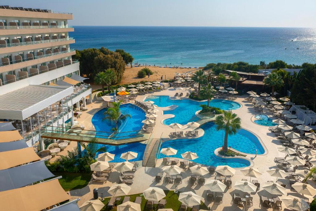 an aerial view of a resort with swimming pools and umbrellas at Melissi Beach Hotel & Spa in Ayia Napa