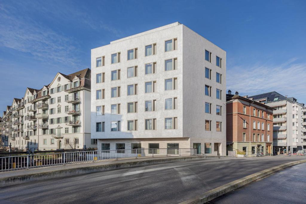 un grand bâtiment blanc sur le côté d'une rue dans l'établissement VISIONAPARTMENTS Neustadtstrasse - contactless check-in, à Lucerne