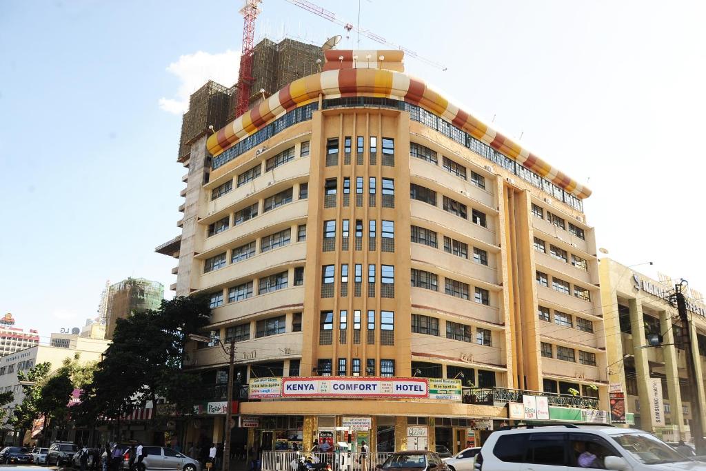 ein hohes Gebäude mit davor geparkt in der Unterkunft Kenya Comfort Hotel in Nairobi