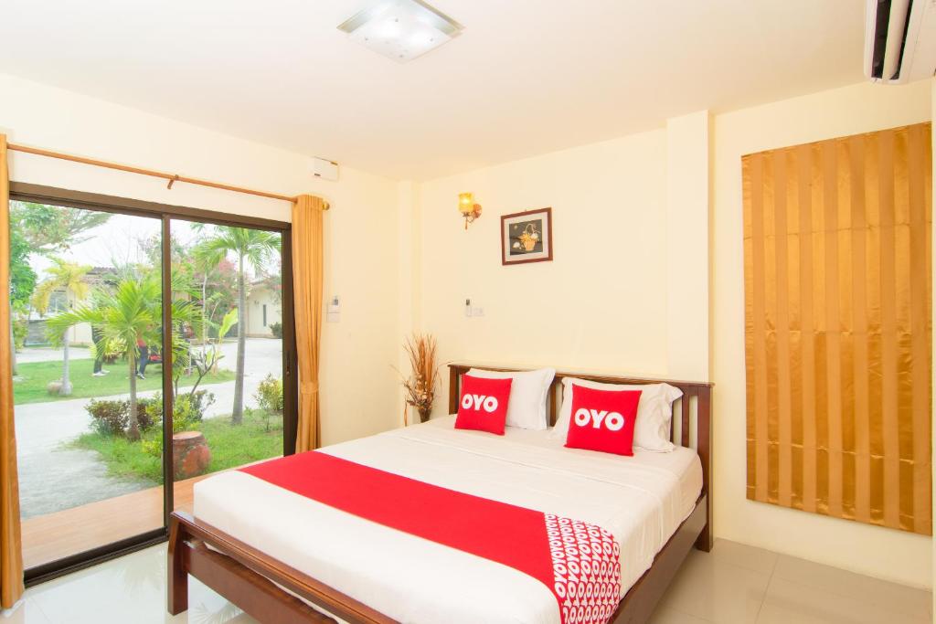 sypialnia z łóżkiem z czerwonymi poduszkami i oknem w obiekcie OYO 607 Nawang Resort w mieście Hua Hin