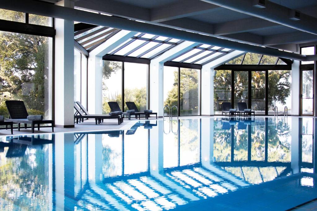 a large swimming pool with chairs and windows at Meliá Castelo Branco in Castelo Branco