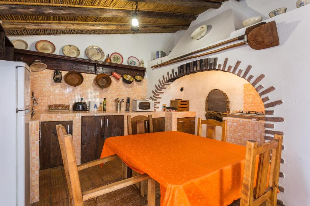eine Küche mit einem orangefarbenen Tisch und einem Kühlschrank in der Unterkunft Casa Do Forno - Quinta Amoreira in Faro