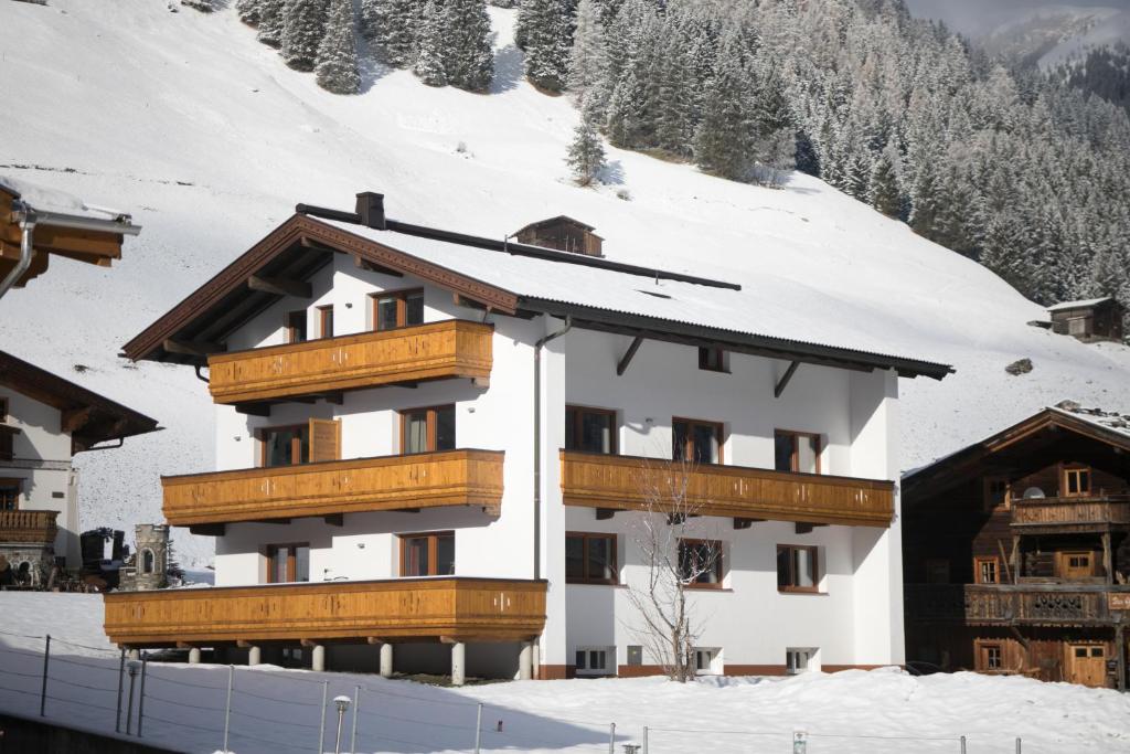 ein Gebäude mit Holzbalkonen im Schnee in der Unterkunft Apart Jöchler in Tux