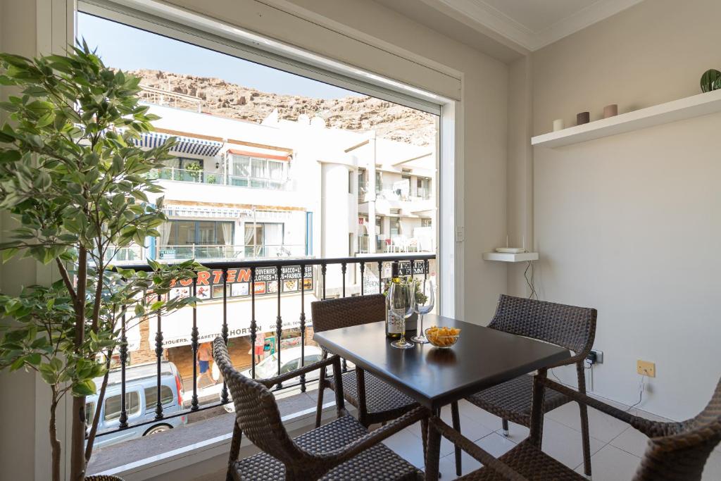 a dining room with a table and chairs and a large window at Amarre Fuente in Puerto de Mogán