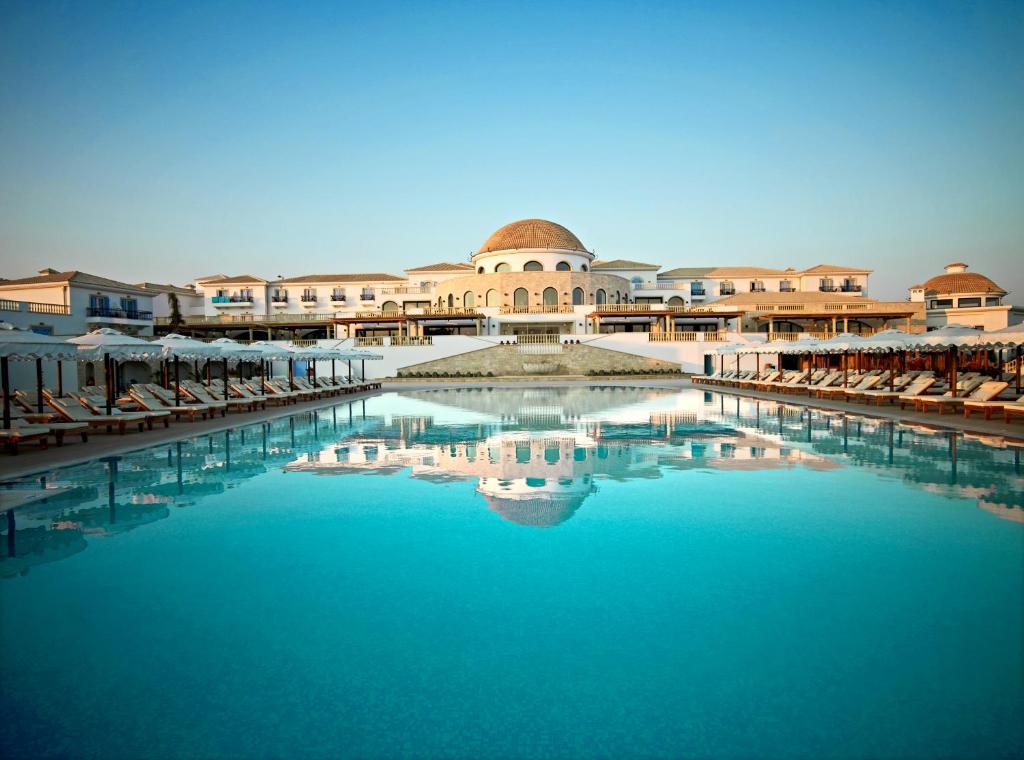 uma grande piscina de água com cadeiras e um edifício em Mitsis Selection Laguna em Hersonissos
