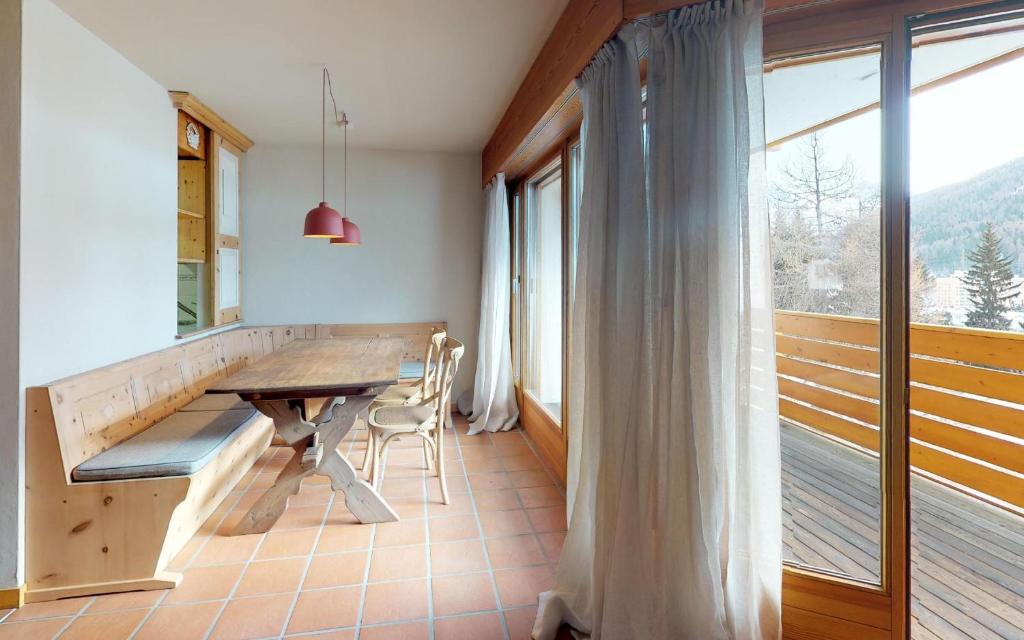 una sala da pranzo con tavolo e una grande finestra di Madulaina 6B a Sankt Moritz