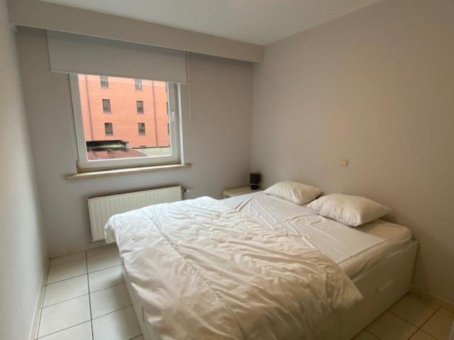 - un lit blanc dans une chambre avec fenêtre dans l'établissement Residentie Kompas 102, à Nieuport