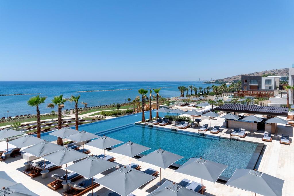 an aerial view of a resort pool with umbrellas and the ocean at Amara - Sea Your Only View™ in Limassol