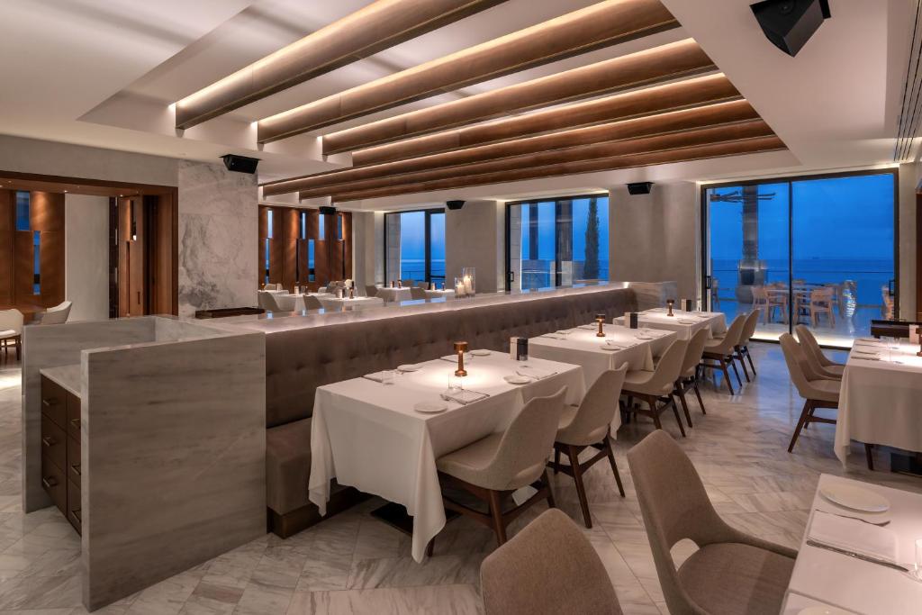 a dining room with tables and chairs and windows at Amara - Sea Your Only View™ in Limassol